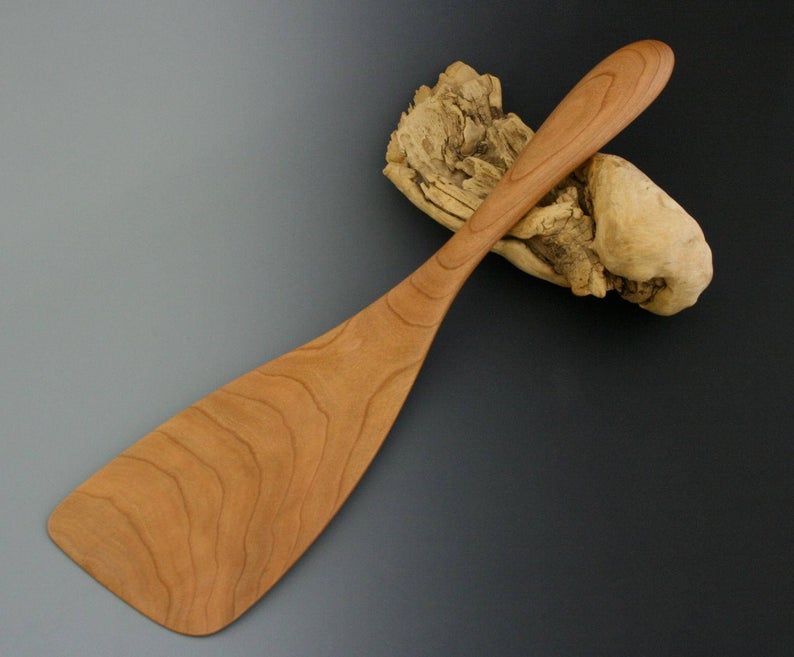 Large cherry wood turner spatula with wide blade and thin beveled edge.