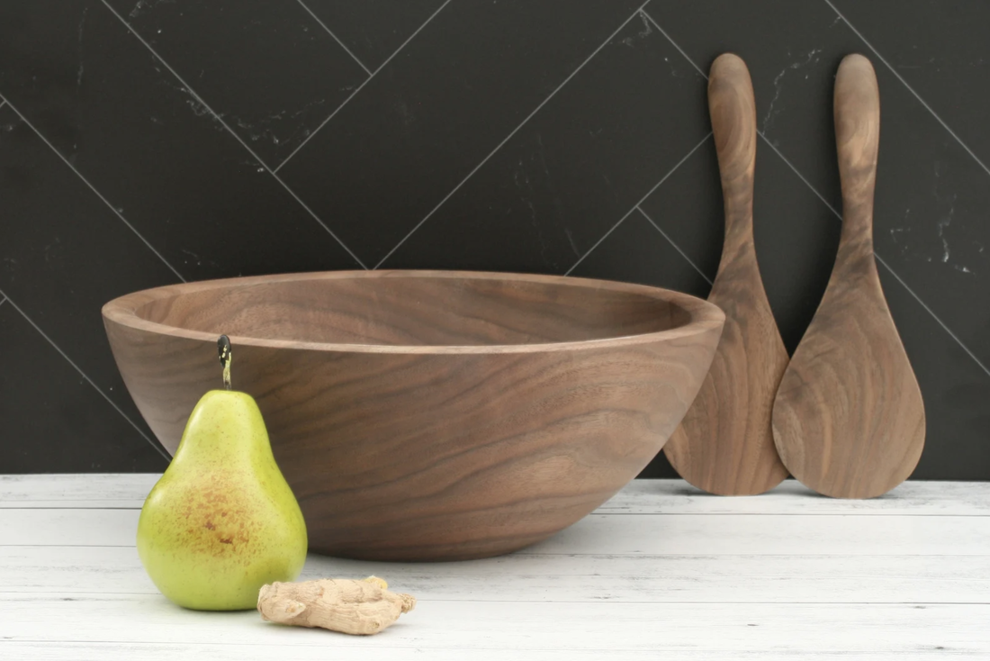 Large black walnut serving bowl and serving paddles to serve two on a white barnwood counter top and black marble back splash.