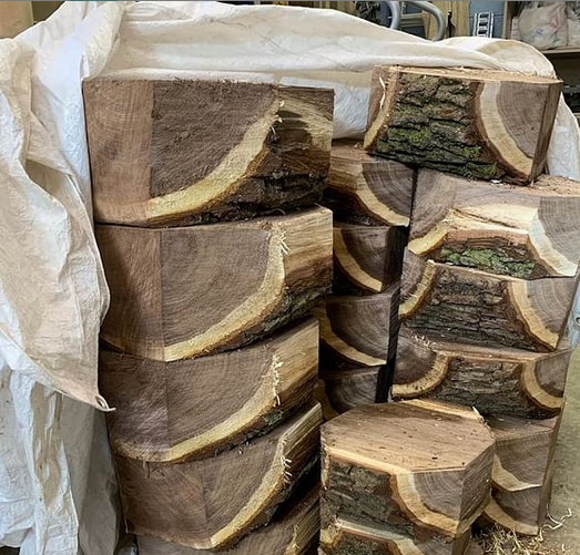 Stack of walnut wood logs with bark cut into bowl blanks.